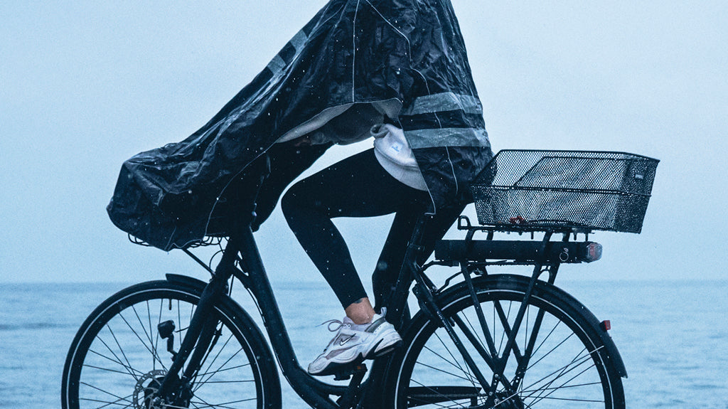 Cyclist wearing a cycling poncho and helmet during a rainy commute