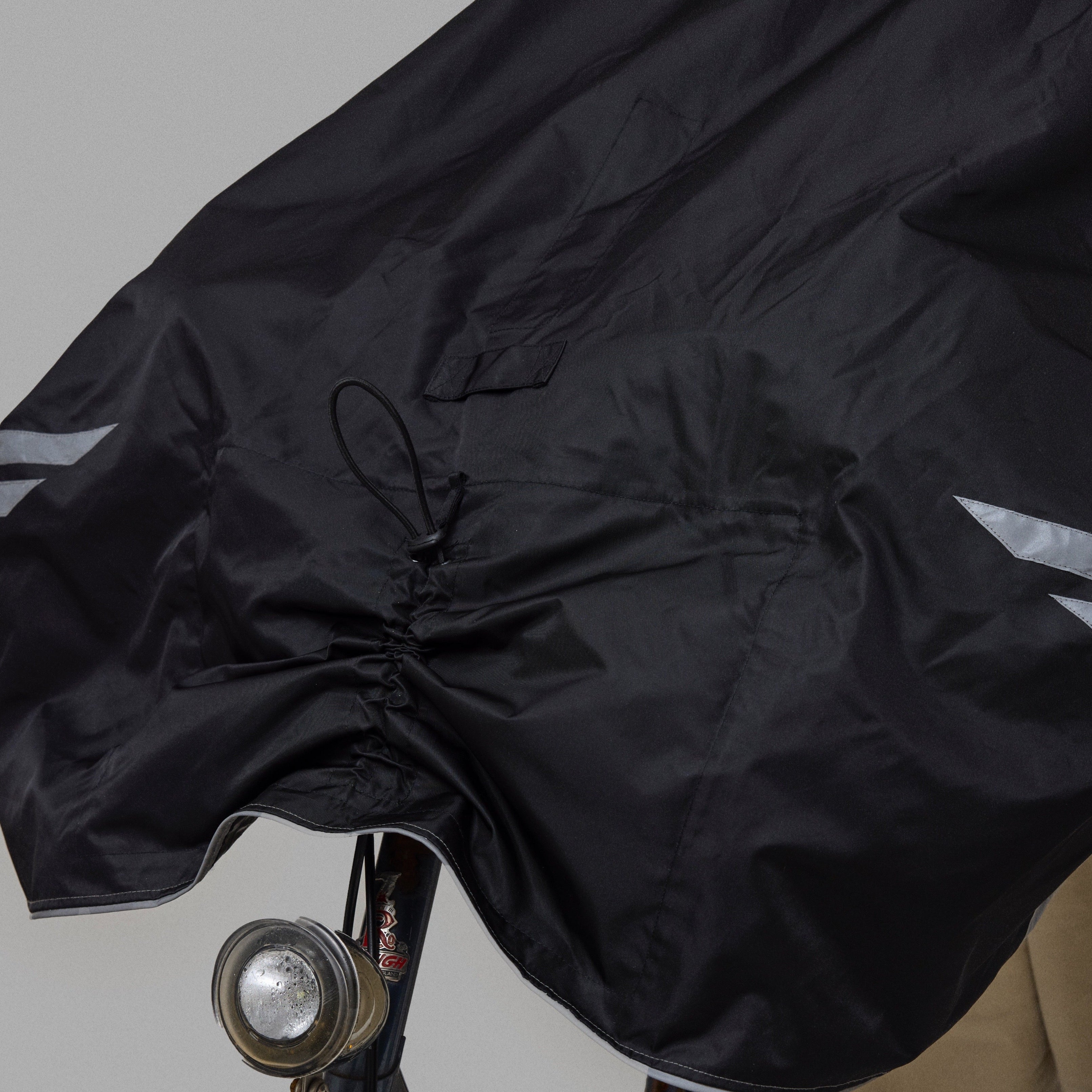Black NoRain Bicycle poncho draped over a bicycle on a gray background