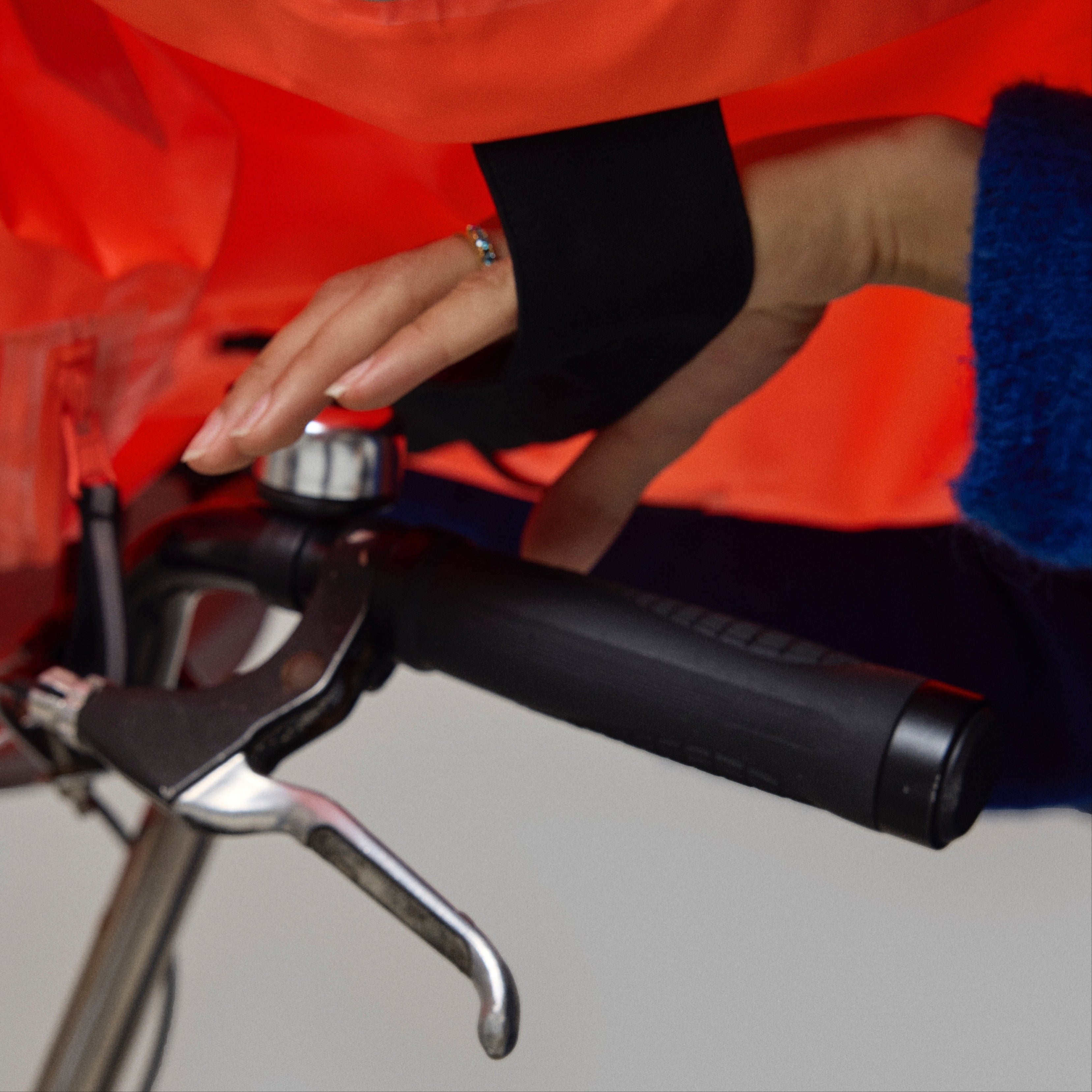 Close-up of a bicycle handlebar with a orange NoRain bicycle poncho in the background