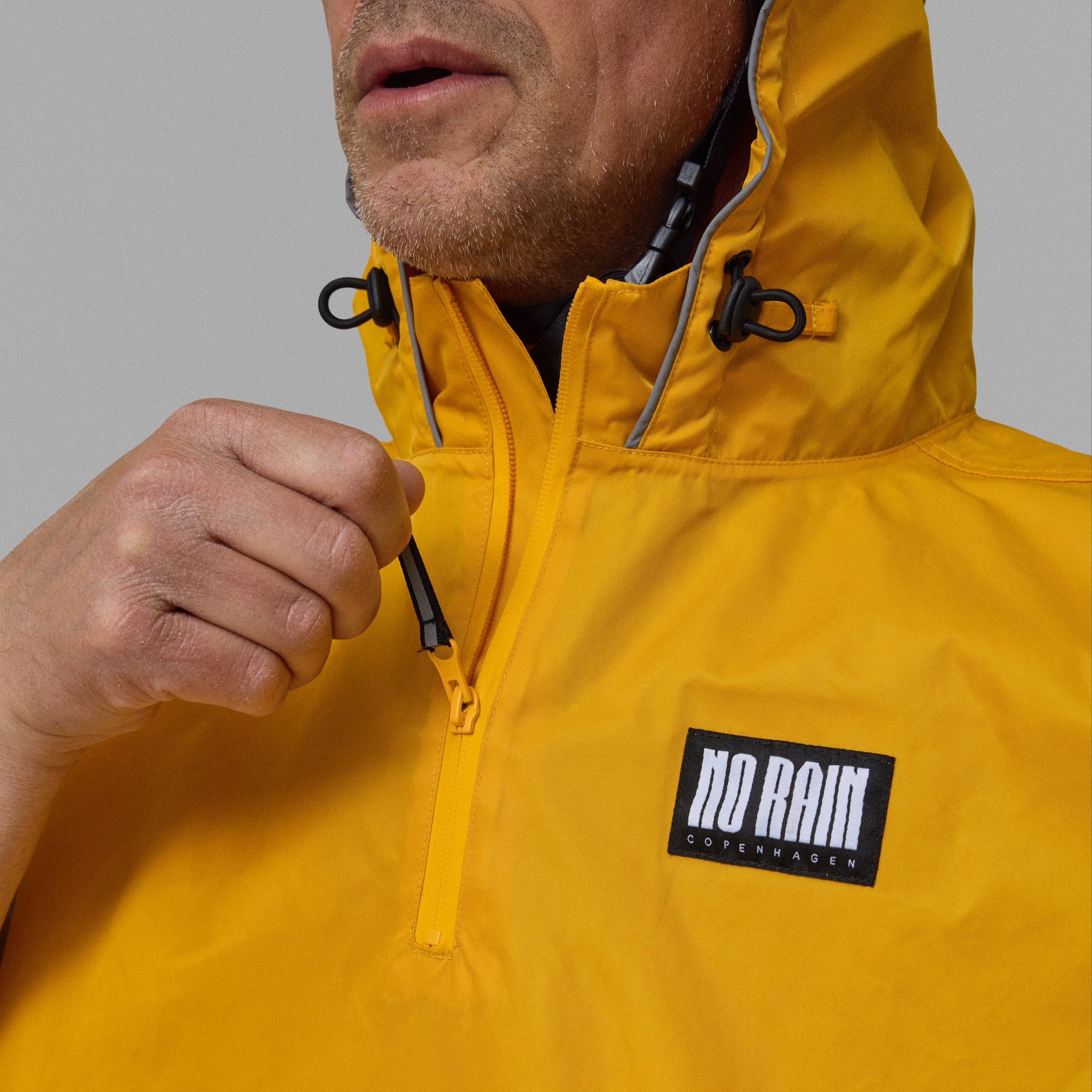 Yellow NoRain bicycle poncho with a brand logo on a gray background