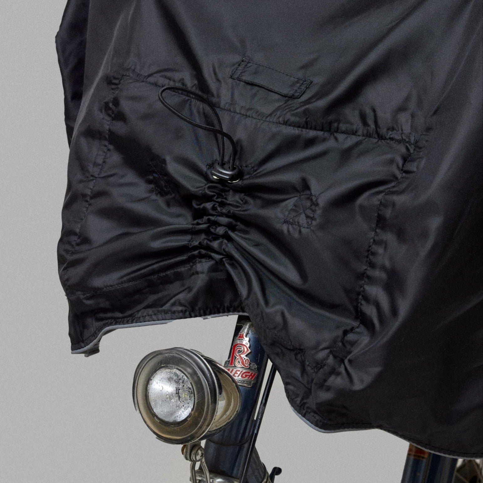 Black bike rain poncho on a bicycle against a gray background