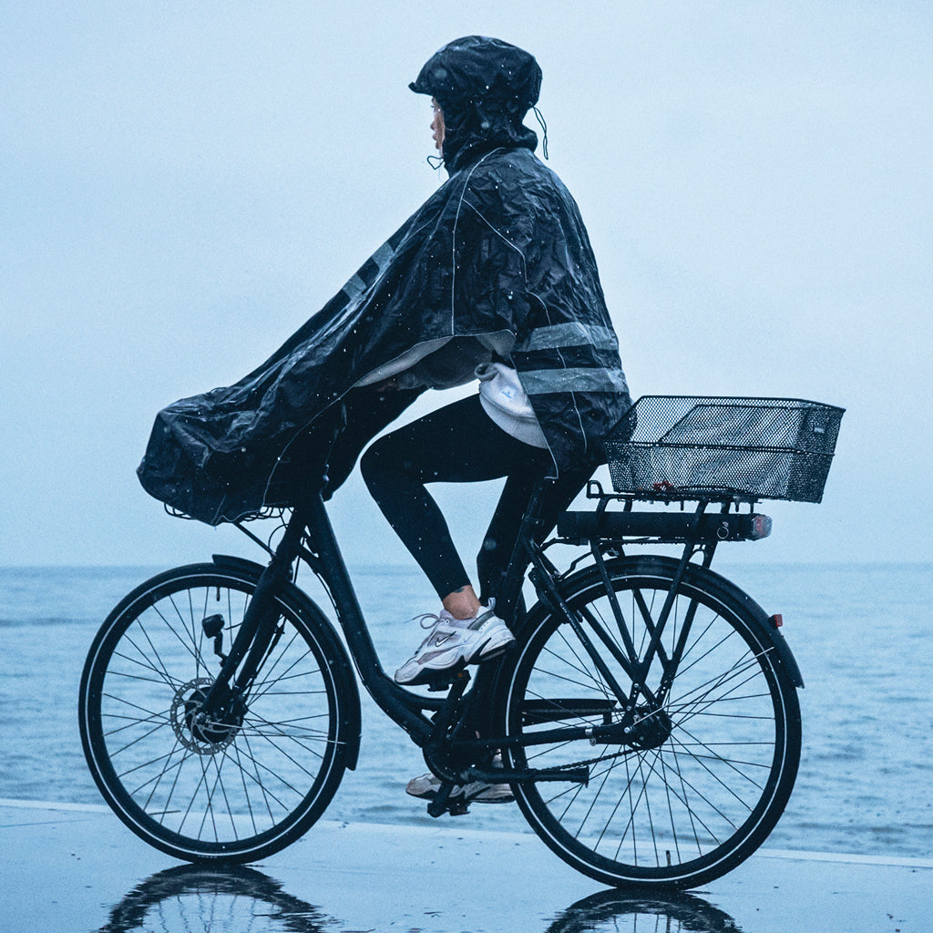 Cyclist wearing a cycling poncho and helmet during a rainy commute