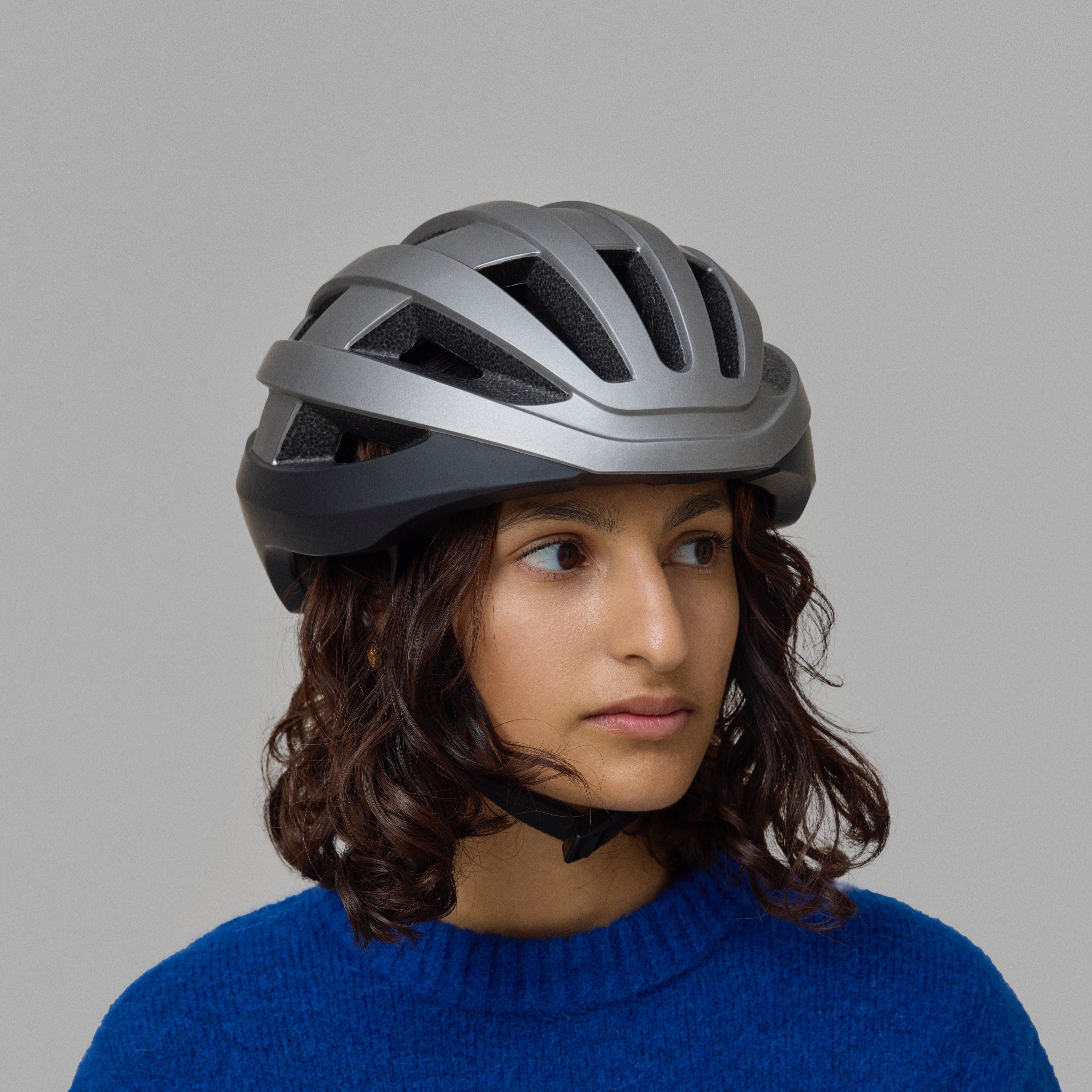 Person wearing a gray and black NoRain bicycle helmet against a gray background