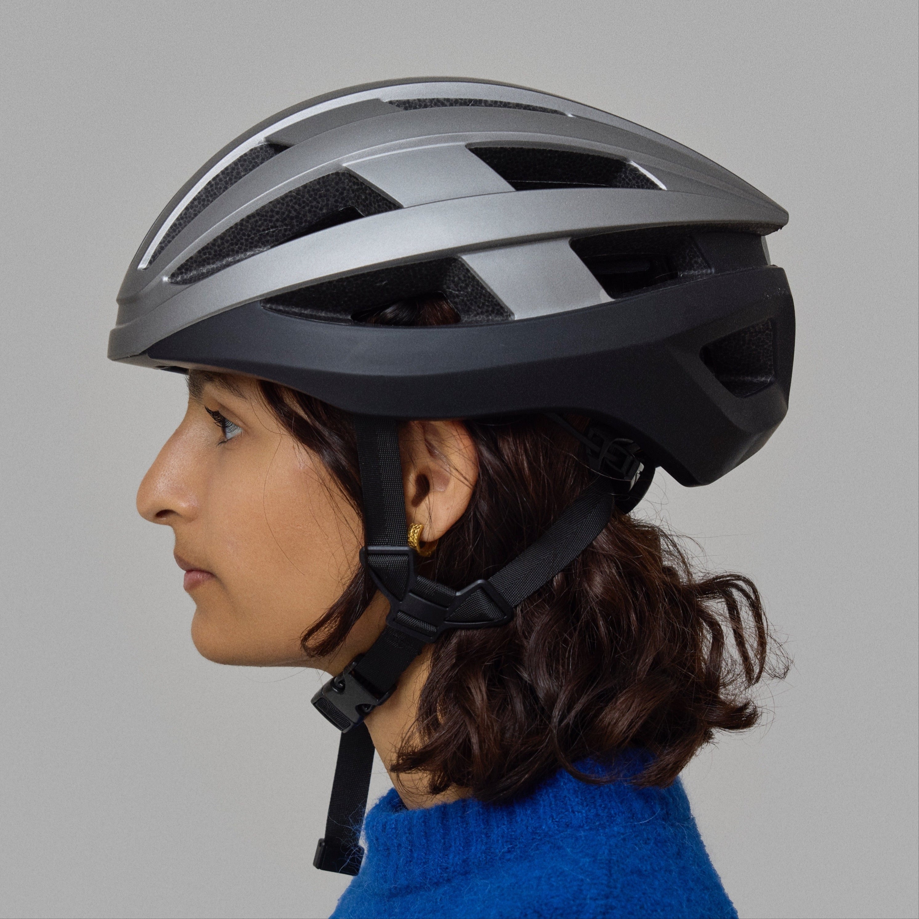 Person wearing a black and silver NoRain bicycle helmet on a gray background