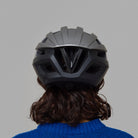 Person wearing a black Norain bicycle helmet from behind on a gray background