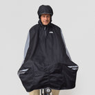 Person wearing a black NoRain bicycle poncho on a bicycle against a white background