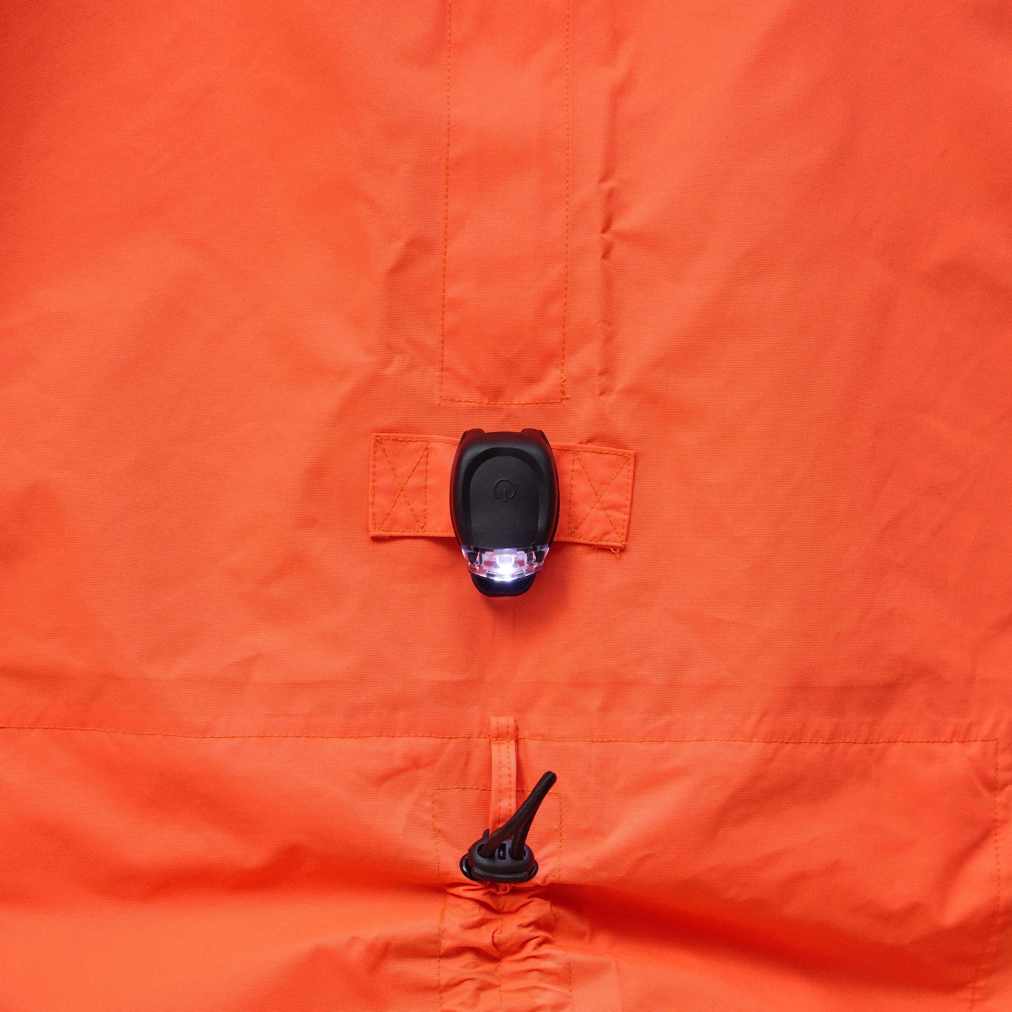 Close-up of an orange jacket with a zipper and button detail