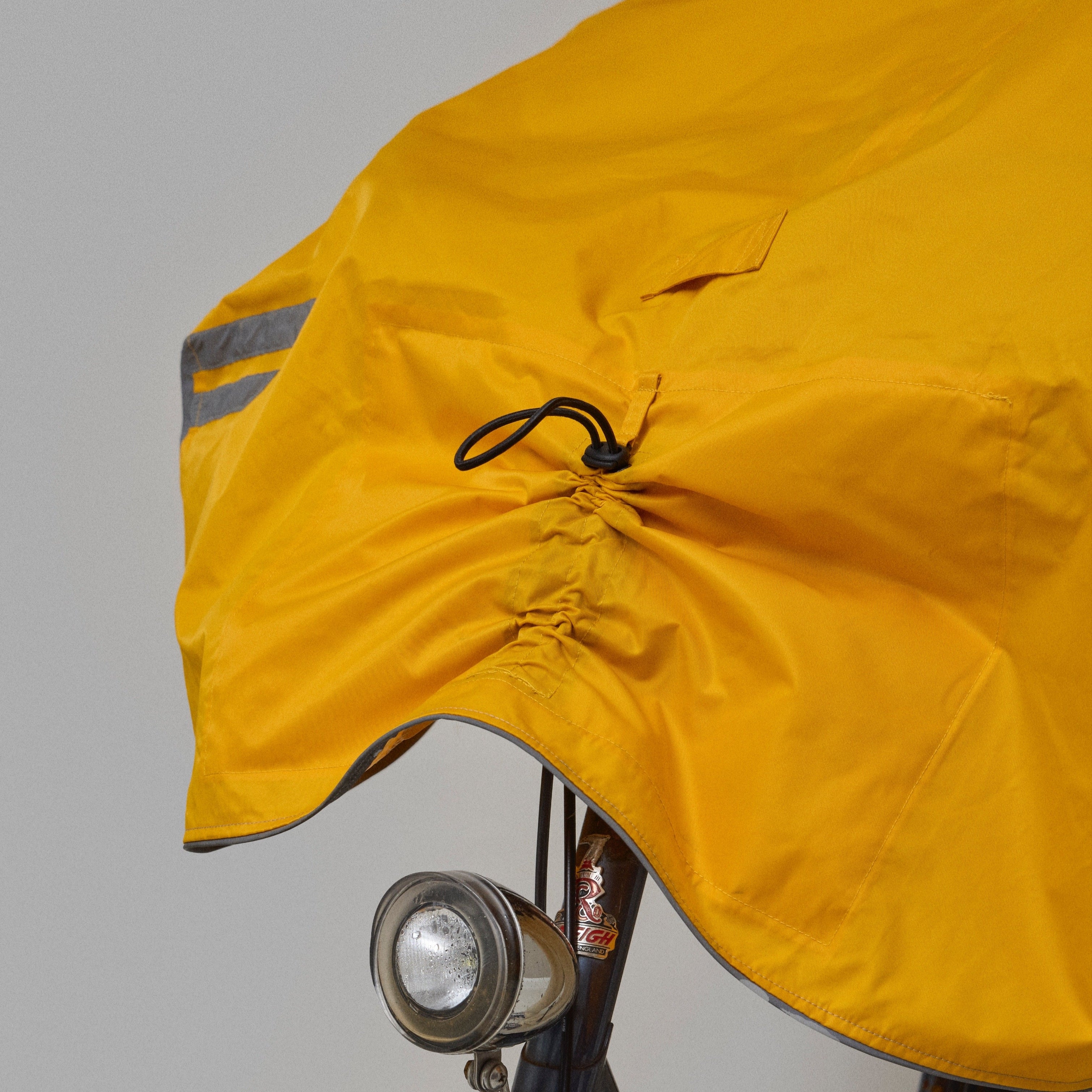 Yellow NoRain bicycle poncho  draped over a bicycle against a plain background