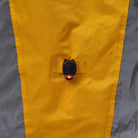Close-up of a yellow and gray NoRain bicycle poncho  with a button on a neutral background