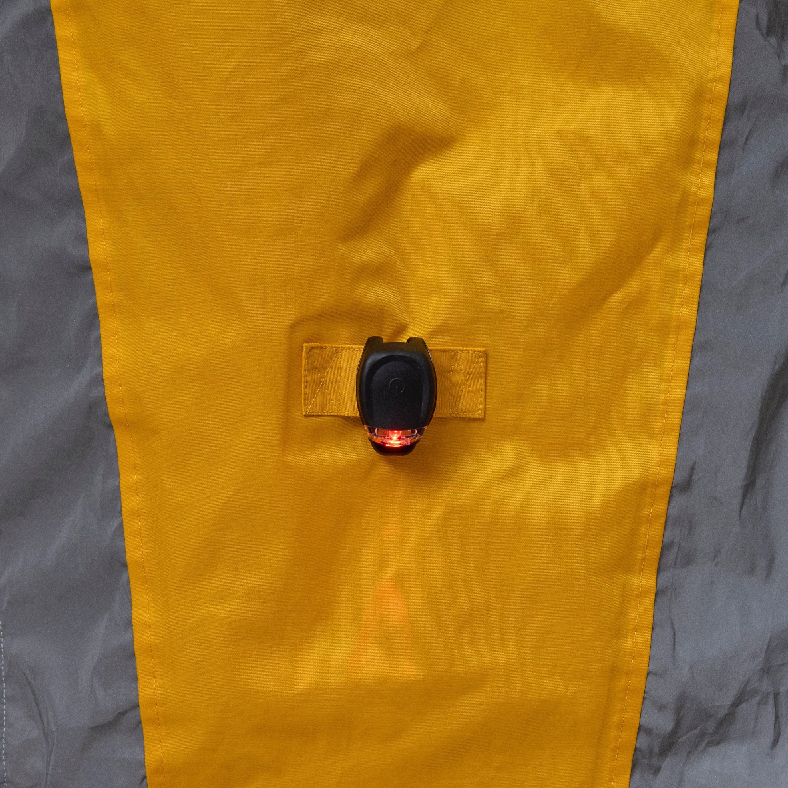 Close-up of a yellow and gray NoRain bicycle poncho  with a button on a neutral background