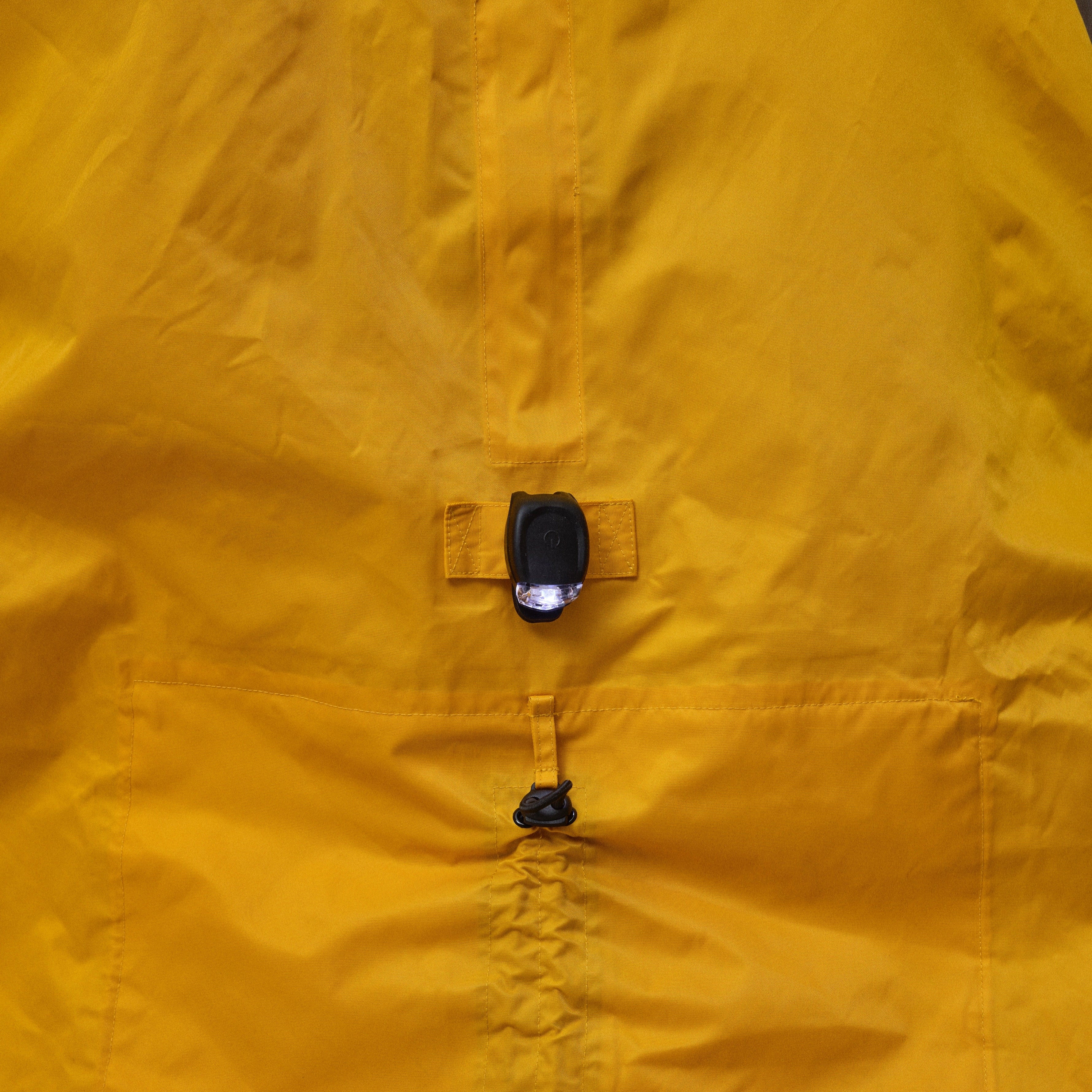 Close-up of a yellow NoRain bicycle poncho  with a buttoned front on a plain background